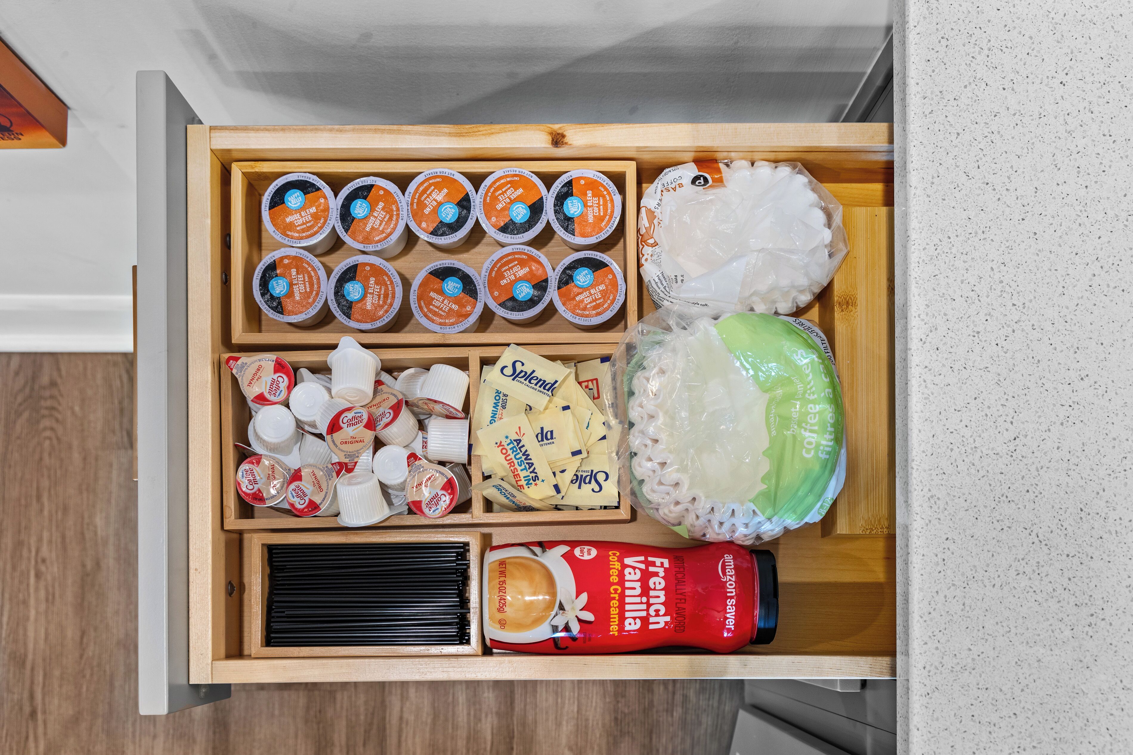 A drawer containing various coffee-related items including coffee creamer, coffee pods, and a coffee grinder.
