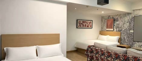 Una habitación de hotel con una cama grande, una cama más pequeña, un sofá y un televisor.