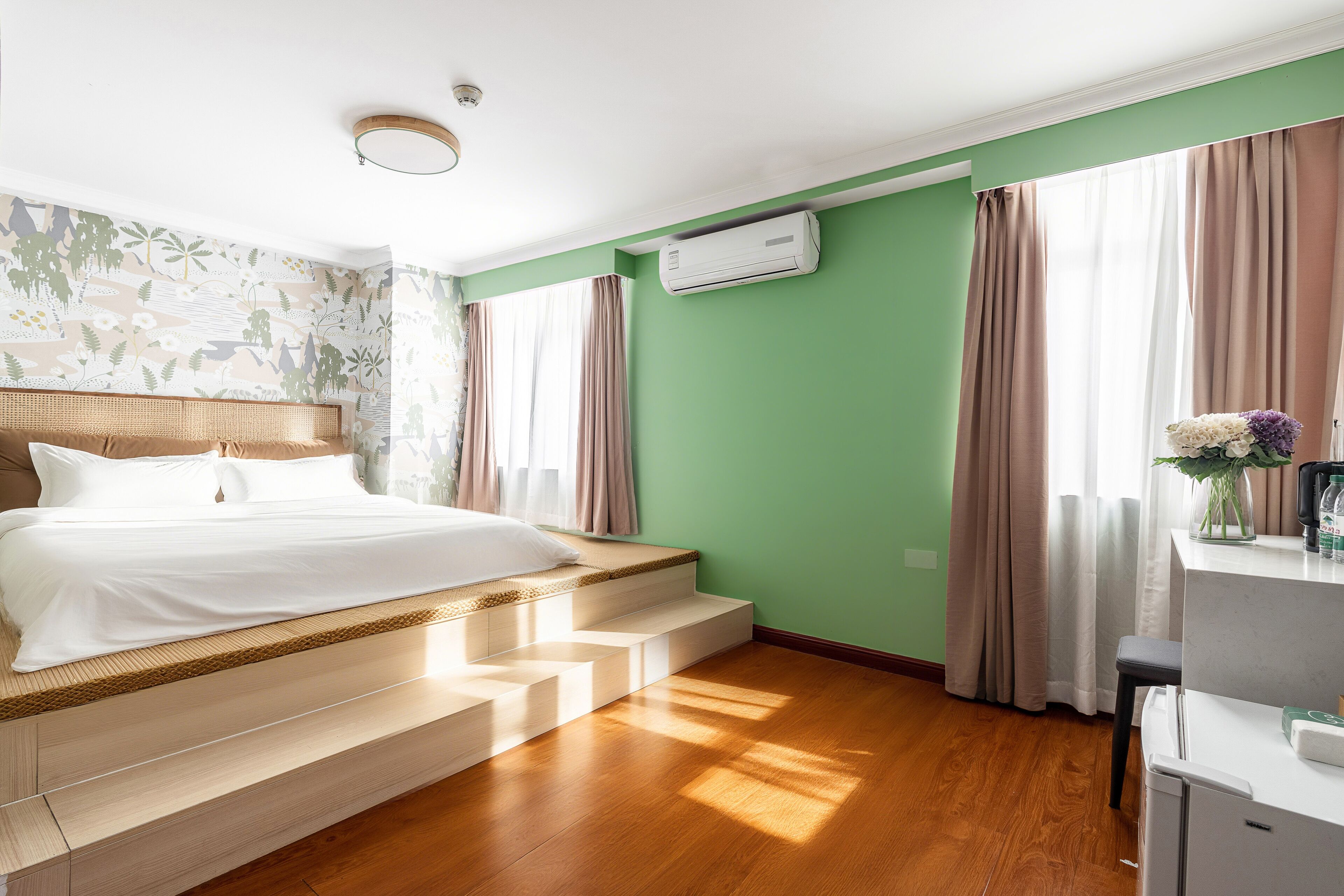 A bedroom with a bed, a desk, and a window with curtains.