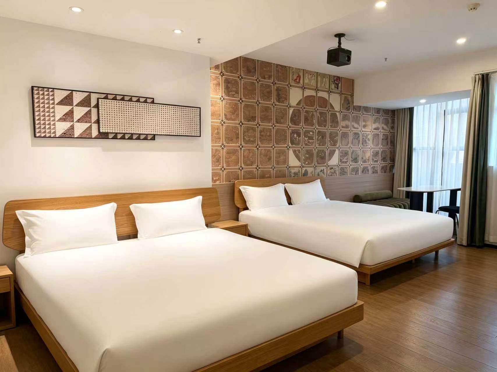 A hotel room with two beds, a large wall mural, and a window with curtains.