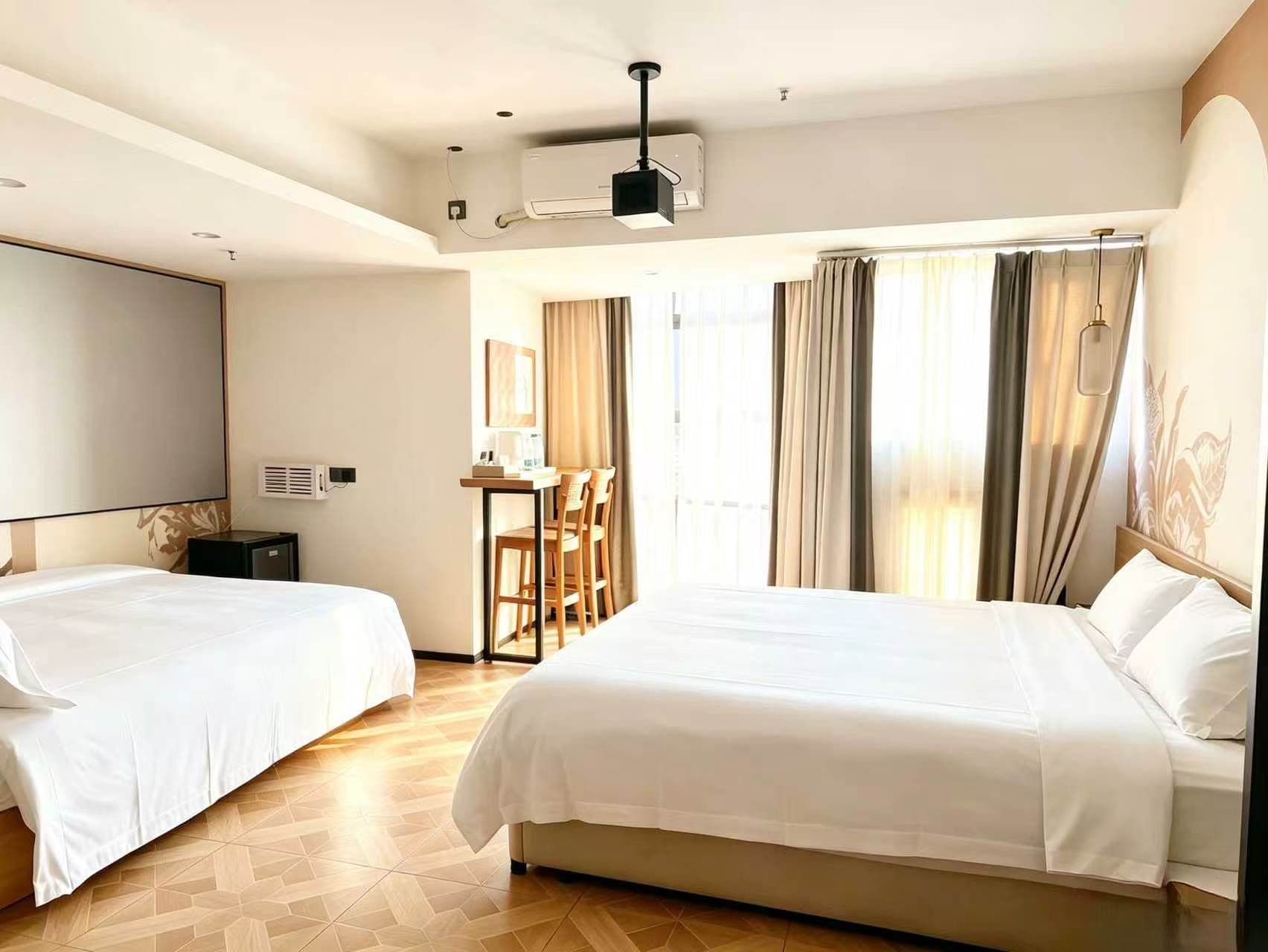 A hotel room with two beds, a desk, and a large window with curtains.