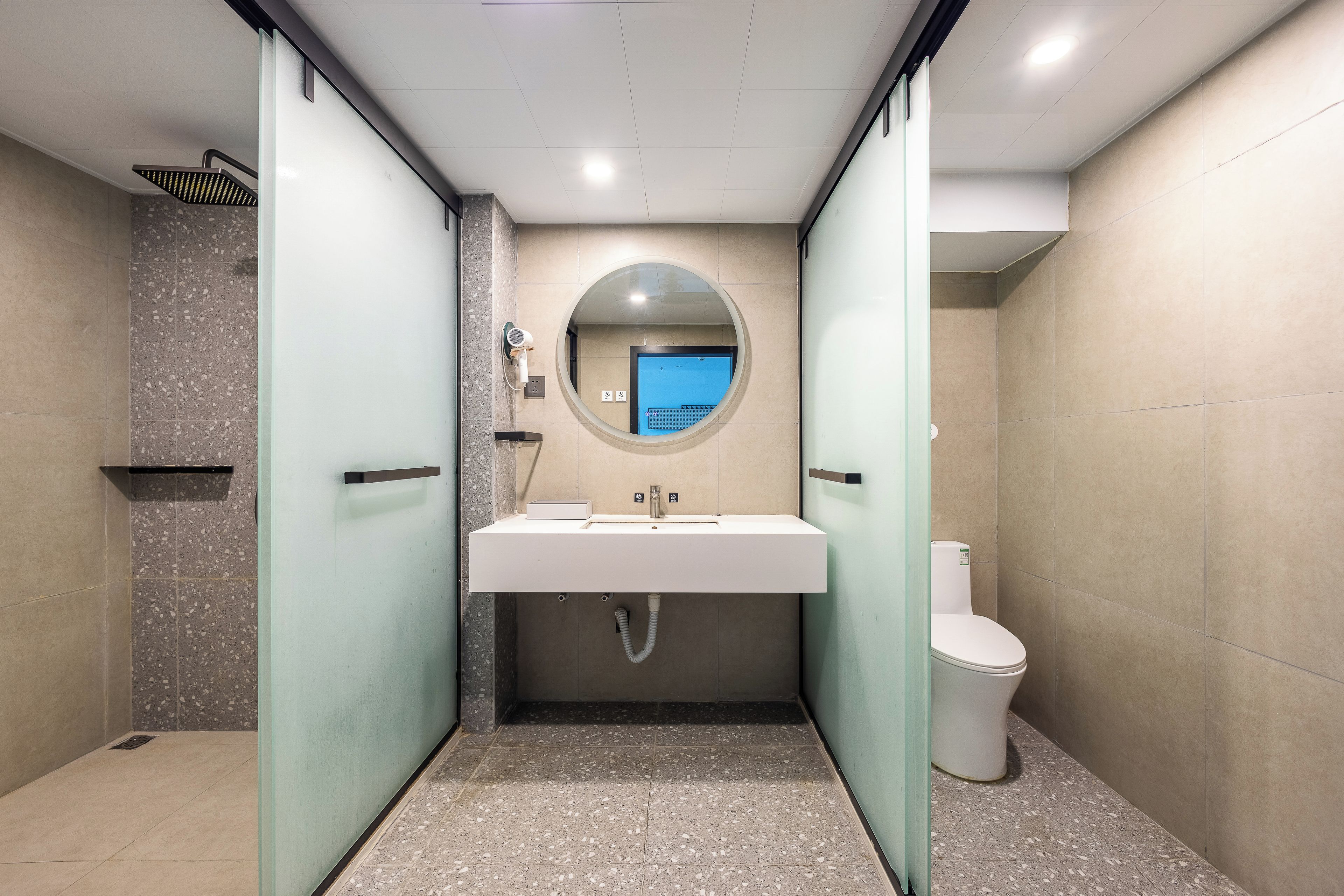 A modern bathroom with a glass-enclosed shower, a sink with a mirror above, and a toilet.