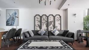 A modern living room with a grey sofa, black and white patterned rug, and a painting of a peacock. - VanInn Guangzhou , Step Out to Beijing Road Pedestrian Street , Gongyuanqian & Beijing Road Metro - Canton Fair (Guangzhou)
