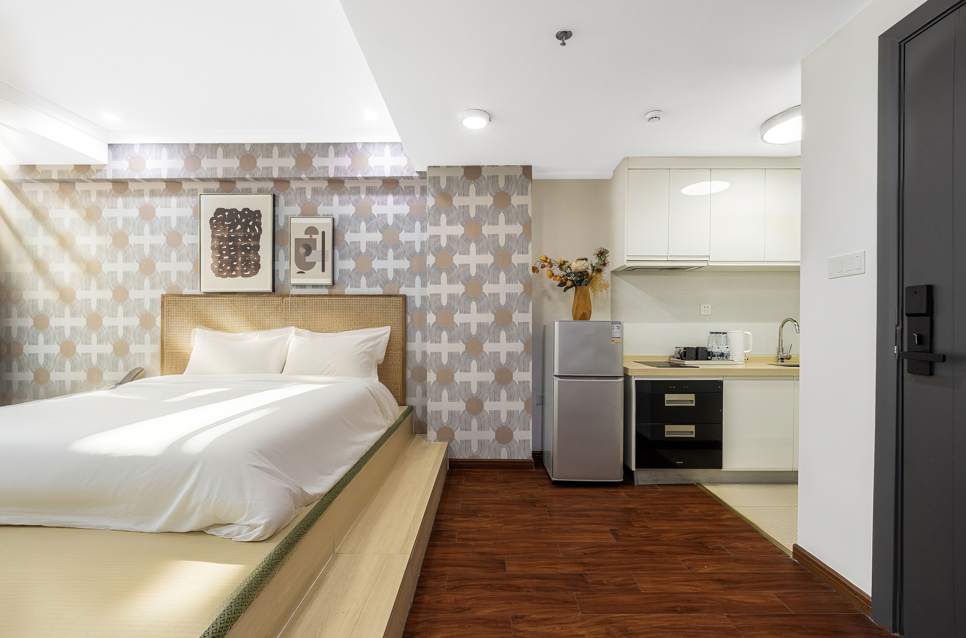 A hotel room with a bed, a kitchenette, and a bathroom.