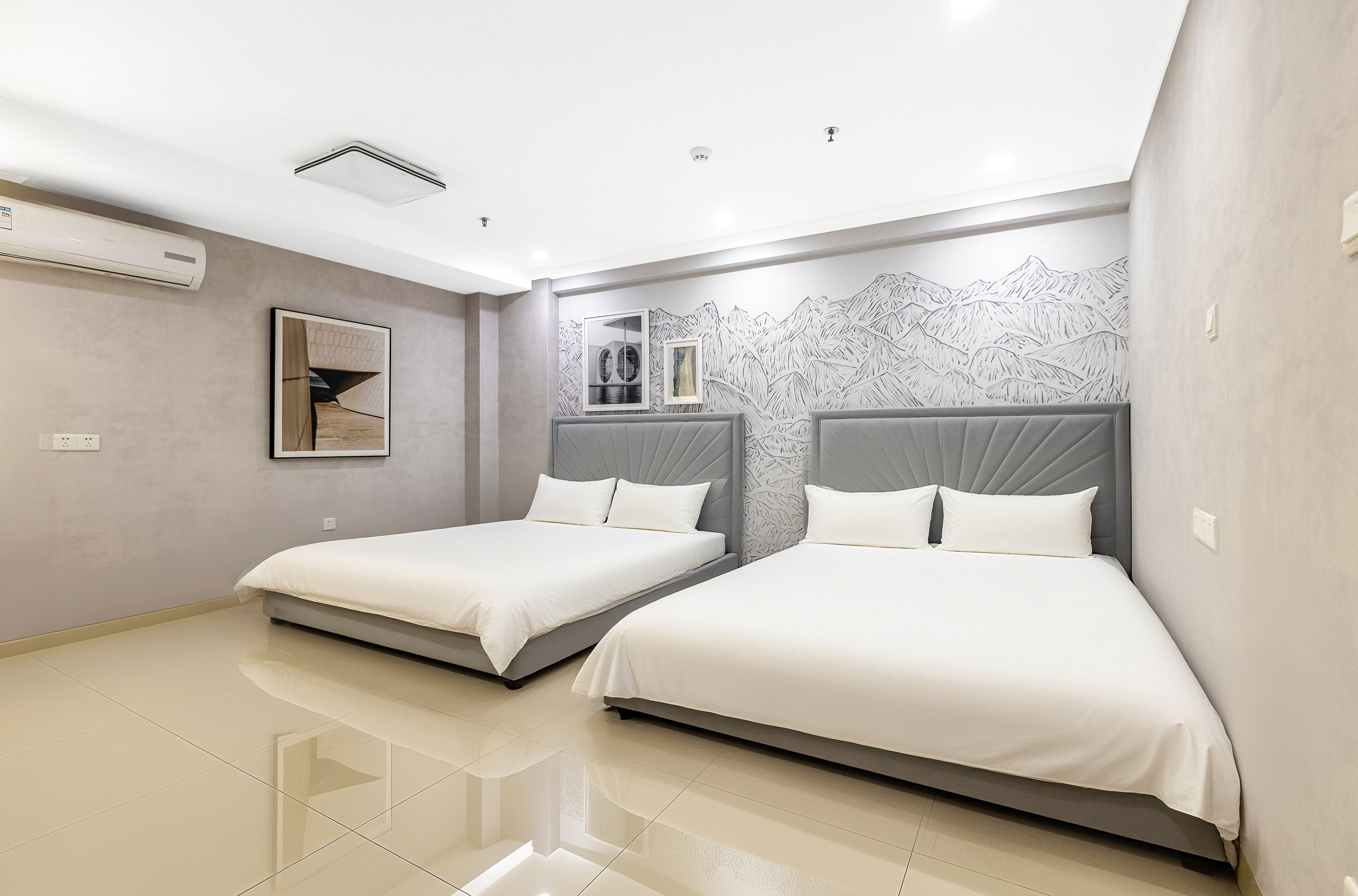 A modern hotel room with two beds, a large window, and a mountain mural on the wall.