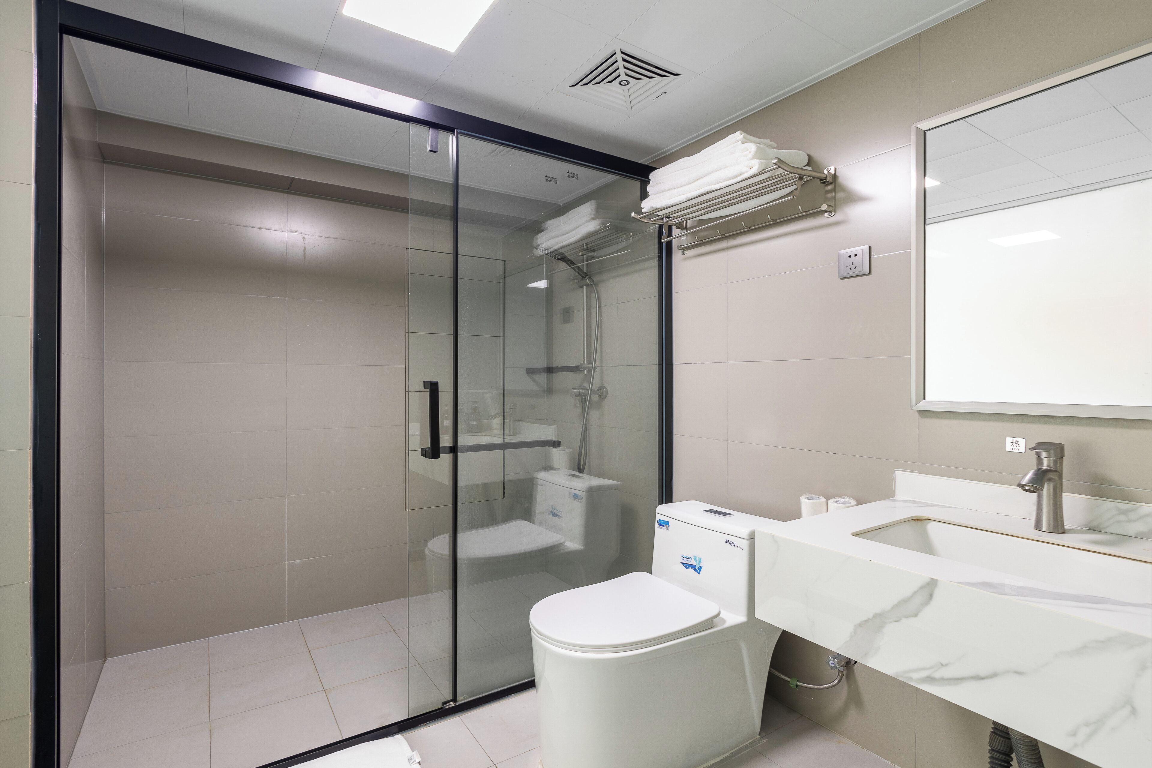 A modern bathroom with a glass-enclosed shower, a white toilet, and a marble sink.