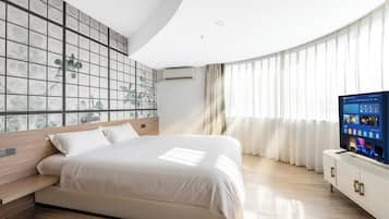 A modern bedroom with a large bed, a TV on a white cabinet, and a wall with a grid pattern.