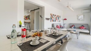 Un soggiorno moderno con zona pranzo, un divano grigio e un tavolino da caffè.