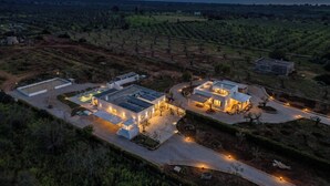 Una vista aerea di una zona residenziale moderna con due edifici principali, una piscina e un vigneto sullo sfondo.