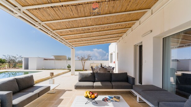 Una zona relax esterna con piscina, un portico coperto e un'area salotto.