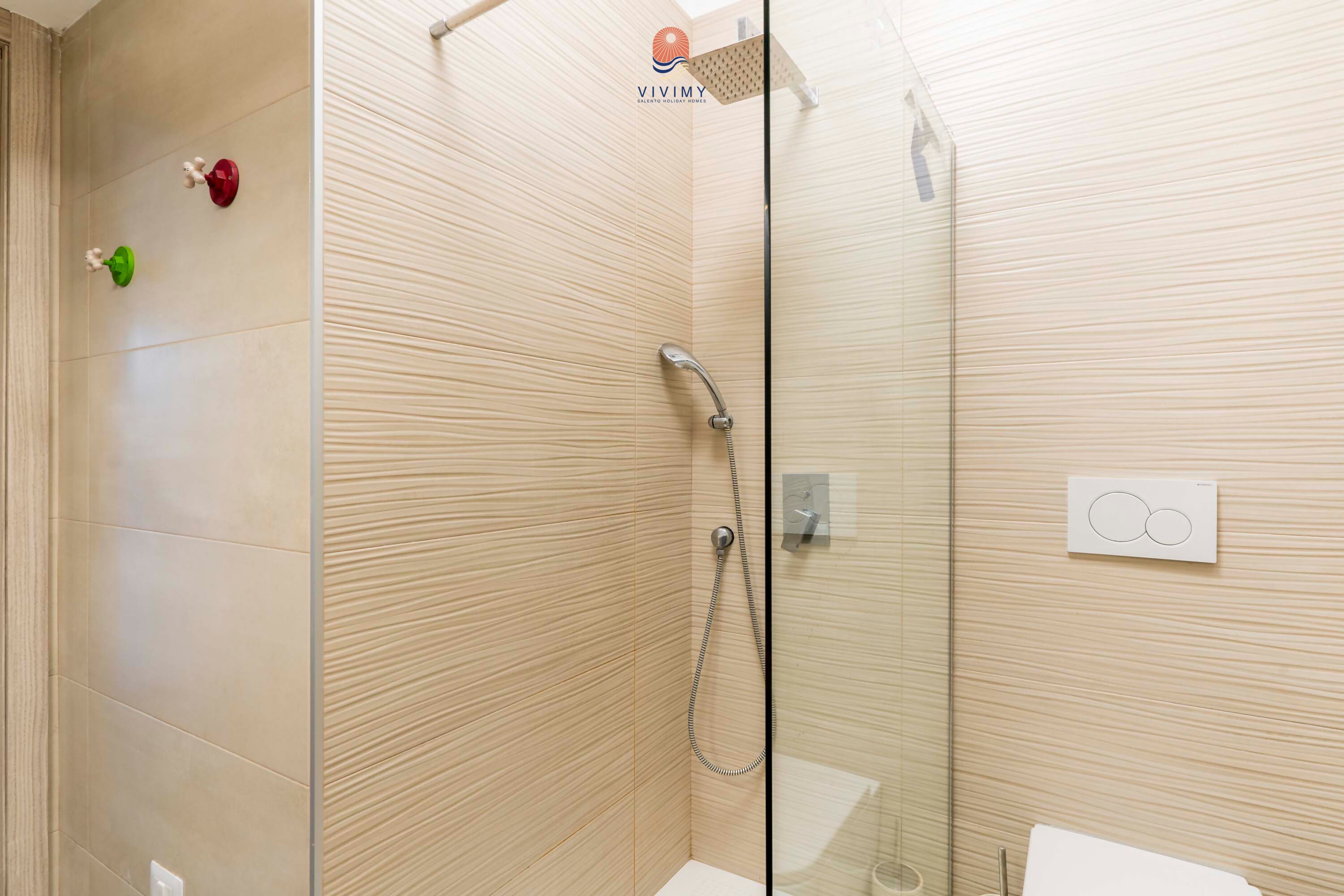A modern bathroom with a glass shower enclosure, a toilet, and a wall-mounted towel rack.