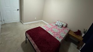 Una camera da letto con un letto, una coperta rossa, un comodino e una porta.