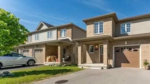 Una casa residenziale a due piani con garage, un portico coperto e vialetto.