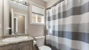 Un bagno con lavandino, specchio, water e tenda doccia.