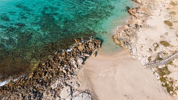 An aerial view of a beach with clear turquoise water, rocky shoreline, and a sandy beach area. - Rustic Dwelling by Vivimy (Ugento)