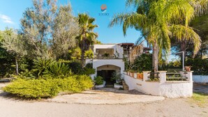 A two-story building with a white facade, a central archway entrance, and a small balcony. - Rustic Dwelling by Vivimy (Ugento)