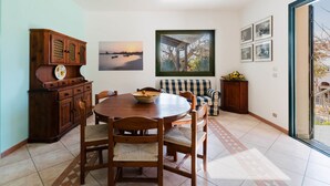 Zona pranzo con tavolo e sedie in legno, un armadio, una poltrona e una finestra vista barche.