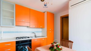 Ett kök med orange skåp, en gasspis och ett matbord med en blomsterdekoration i mitten.