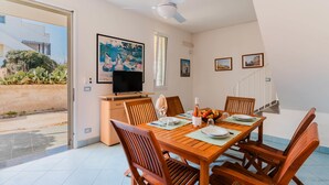 Zona de dinar amb taula de fusta, cadires, televisió i obra d'art a les parets.