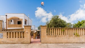 Un bâtiment blanc doté d’un balcon et d’une entrée fermée par un portail.