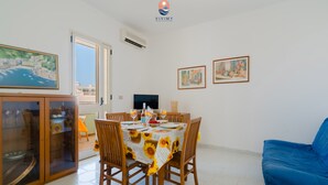 A dining area with a table set for four, surrounded by wooden chairs, a blue sofa, and framed artwork on the walls. - Coral by Vivimy real estate (Gallipoli)