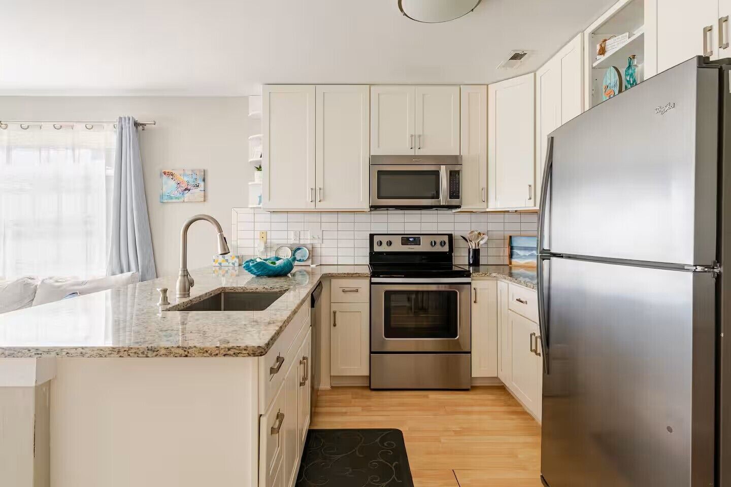 A modern kitchen with white cabinets, stainless steel appliances, and a granite countertop.