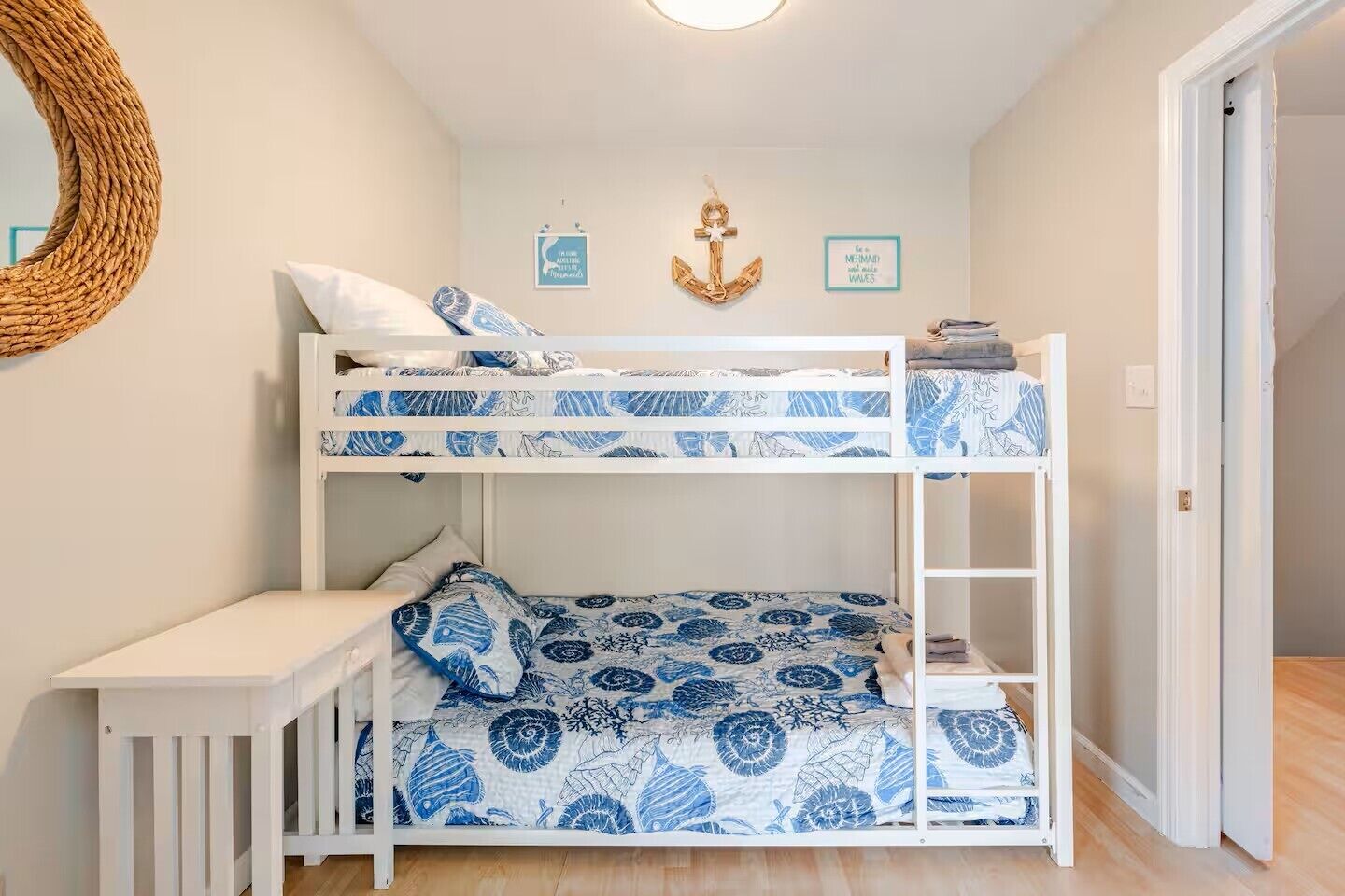 A bunk bed room with a white desk and bunk beds.