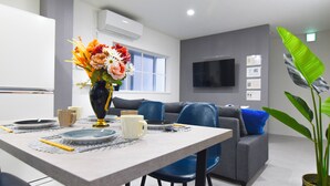 A modern dining area with a table set for four, a sofa, and a large plant. - 1 minute to Universal Studios Japan! Spend a relaxing time in a stylish house with free parking! (Osaka city Konohana-ku Shimaya)