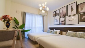 A hotel room with two beds, a dining table, a vase with flowers, and a wall with framed pictures. - 1 minute to Universal Studios Japan! Spend a relaxing time in a stylish house with free parking! (Osaka city Konohana-ku Shimaya)