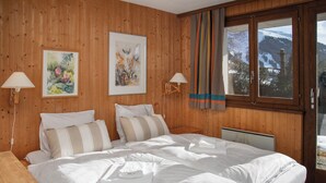 Una habitación con paneles de madera, una cama grande, dos mesitas de noche y una ventana con cortinas.