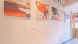 A hallway with abstract paintings on the walls and a logo on the floor. - Il Porto 19 - Mansarda sul Mare (Porto Azzurro)