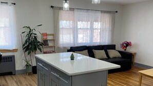A modern kitchen with a central island, wooden flooring, and pendant lighting. - 2-bedroom apartment in cool Bronx with refreshing AC (Bronx)