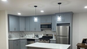 A modern kitchen with grey cabinets, stainless steel appliances, and a central island. - 2-bedroom apartment in cool Bronx with refreshing AC (Bronx)