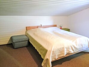 Une chambre à coucher avec un lit, une table de chevet et un pouf.