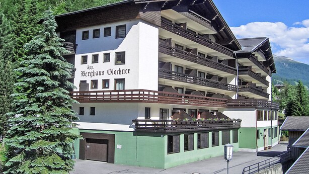 Ein mehrstöckiges Hotel mit Balkonen und einer grünen Fassade, genannt "App. Berghaus Glockner".