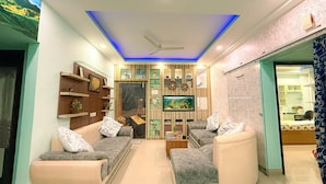 Una sala de estar moderna con un conjunto de sofás, un televisor y una pared decorativa con estanterías.