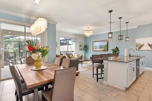 A modern kitchen with a central island, dining area with a wooden table and chairs, and a living area with a sofa and coffee table. - Family Private Pool Villa Near Disney & Universal
BBQ+Resort+LazyRiver+Waterpark (Kissimmee)