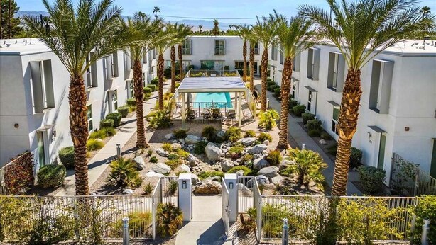 Cortile moderno di un hotel con palme, piscina e zona salotto centrale.