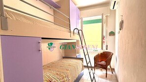 Un dormitorio con literas, una silla y una escalera.