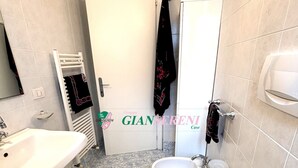 Un baño con lavamanos, inodoro, bidé y perchero para toallas.
