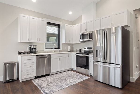 A modern kitchen with white cabinets, stainless steel appliances, a coffee maker, and a dishwasher.