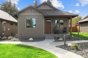 A modern two-story house with a front porch, a stone pathway, and a well-maintained lawn.