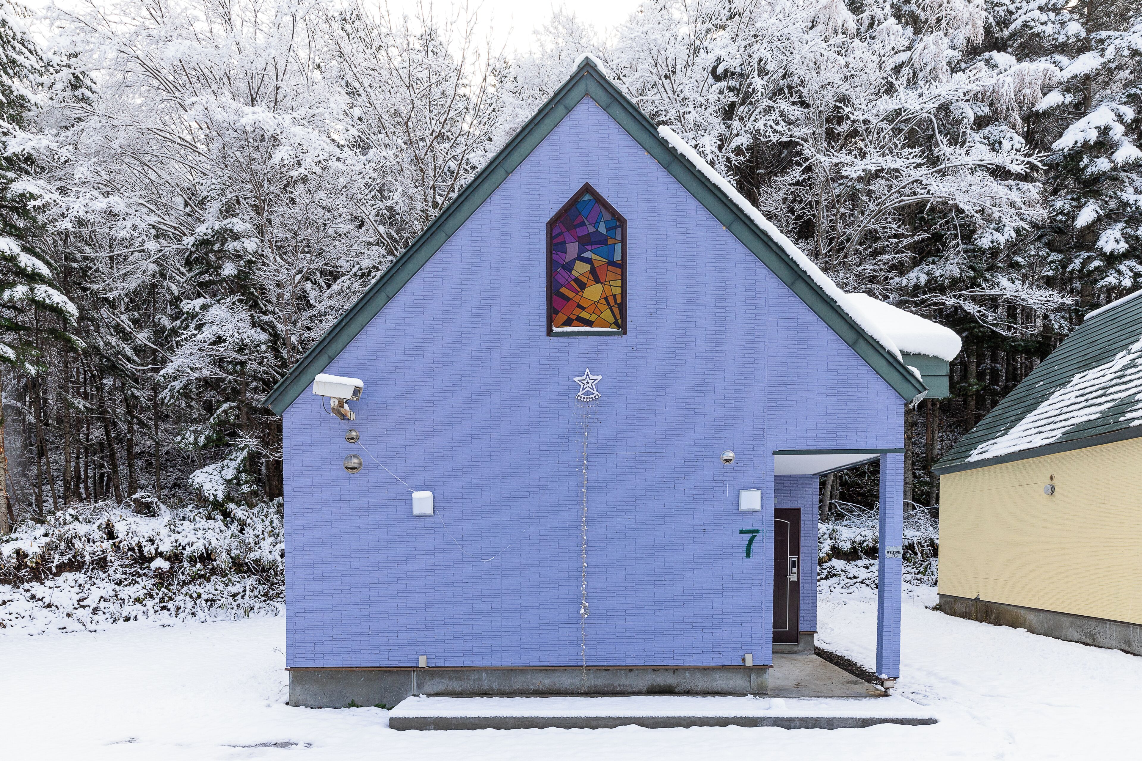 Una iglesia con fachada azul, un vitral y una puerta marcada con el número 7.