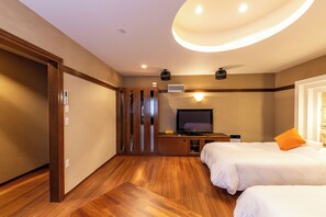 Habitación de hotel con suelo de madera, televisor, cama con almohada naranja y armario.