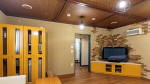 A living room with a wooden ceiling, a television on a wooden stand, and a sofa. - HOTEL FURANO VERDE (Furano)
