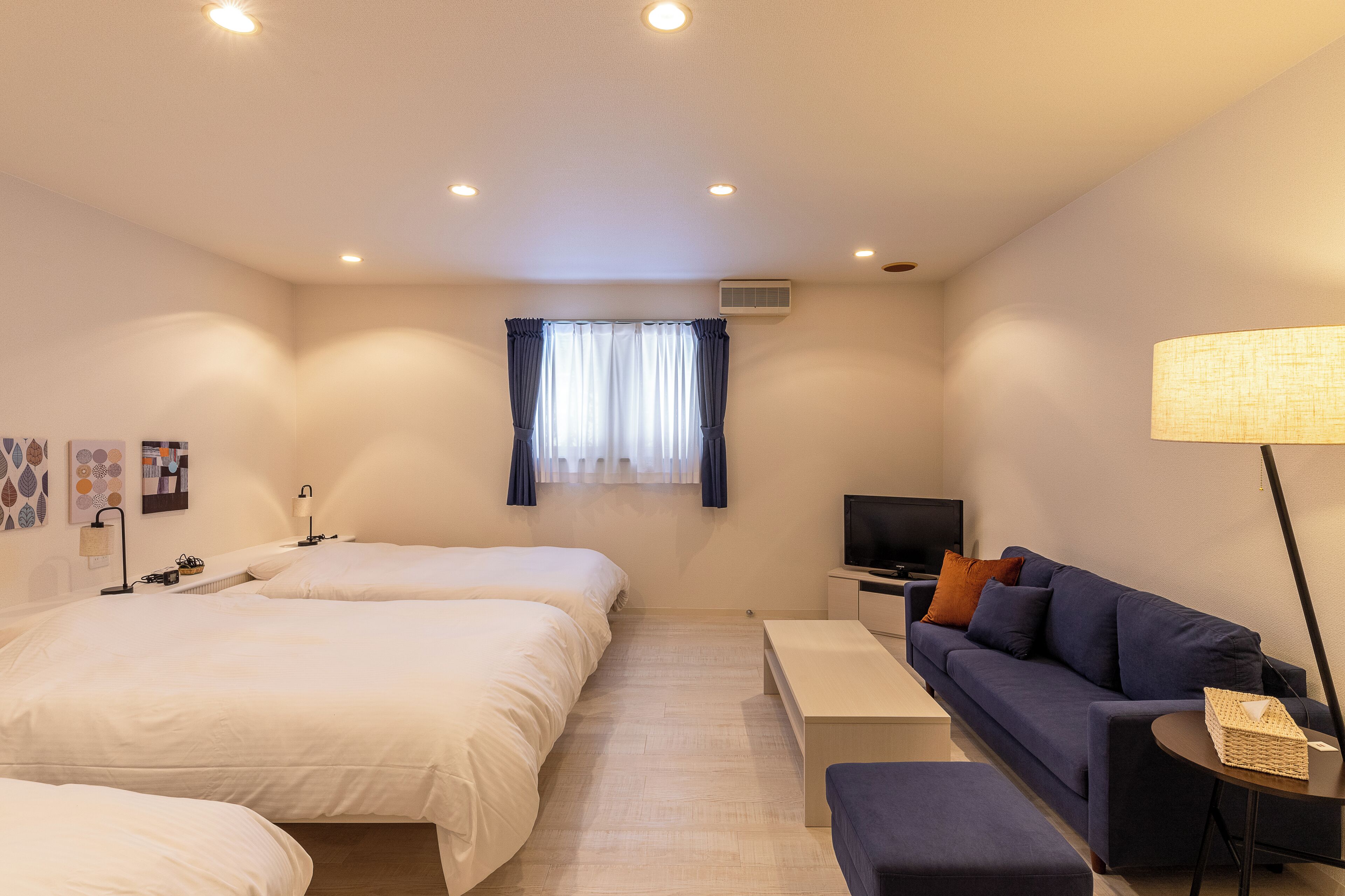 Ein Hotelzimmer mit zwei Betten, einem Sofa, einem Fernseher und einer Lampe.