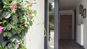 Ingresso moderno di un edificio con una pianta in vaso, una porta in vetro e un corridoio che conduce all'interno.