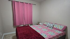A bedroom with a bed, a window with pink curtains, a ceiling light, and a carpeted floor. - Cozy Queen Room Near Hospital | Quiet & Clean Home (Napanee)