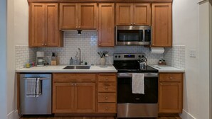 Una cocina con armarios de madera, un microondas de acero inoxidable, un horno y un lavavajillas.