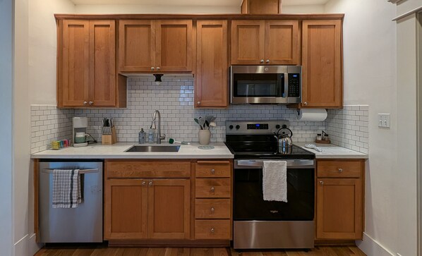A kitchen with wooden cabinets, a stainless steel microwave, an oven, and a dishwasher.